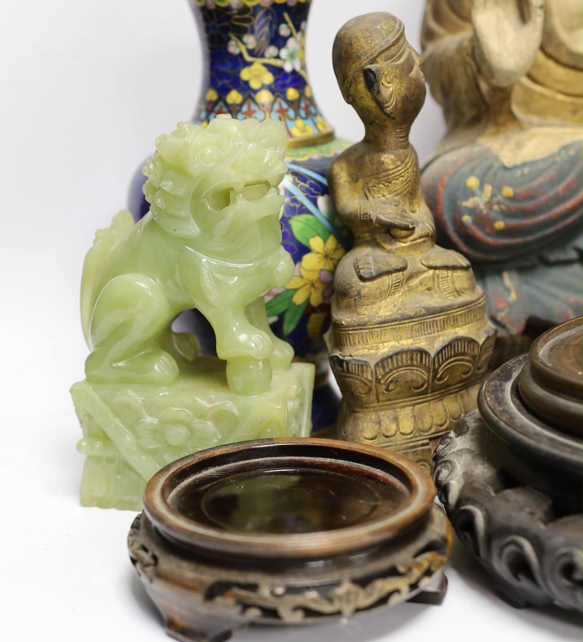 A pair of Chinese cloisonné enamel vases and a bowl on stand, two soap stone lion dogs, a carved and painted Buddha, a deity and four wooden stands, Buddha 33cm high